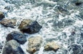 Foamy sea waves on large rocks on the shore. Close-up. Background. Space for text Royalty Free Stock Photo