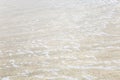 Foamy surface of a sea wave on a sandy beach. Close-up. Background. Space for text