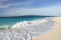 foamy wave on a sandy beach, blue sea water and blue sky with clouds Royalty Free Stock Photo