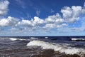 Foamy waves in the Baltic Sea against the blue sky with fluffy clouds Royalty Free Stock Photo