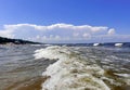 Foamy waves in the Baltic Sea against the blue sky with fluffy clouds in Jurmala Royalty Free Stock Photo