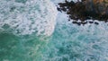 Foamy waves barrelling rocks closeup. Splashing surf water covering black cliffs Royalty Free Stock Photo