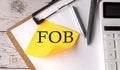 FOB word on a yellow sticky with calculator, pen and clipboard Royalty Free Stock Photo