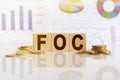 FOC the word on wooden cubes, cubes stand on a reflective surface, in the background is a business diagram