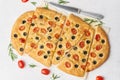 Focaccia, pizza with tomatoes, olives and rosemary. Piece of Italian flat bread. Top view, white concrete background Royalty Free Stock Photo