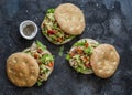Focaccia sandwich with green salad, grilled chicken, avocado tomato salsa and yogurt sauce on dark background, top view Royalty Free Stock Photo