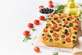 Focaccia with tomatoes, olives and rosemary, copy space, side view. Whole Italian flat bread, bottle with oil Royalty Free Stock Photo