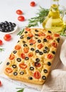 Focaccia with tomatoes, olives and rosemary, vertical. Whole Italian flat bread, bottle with oil Royalty Free Stock Photo