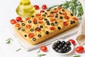 Focaccia with tomatoes, olives and rosemary. Whole Italian flat bread, bottle with oil Royalty Free Stock Photo