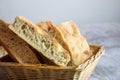 Italian bread of Focaccia Genovese type on display on a basket on a wooden table, sliced in squared pieces.