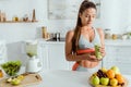 Focus of attractive girl with sportswear holding glass with tasty smoothie