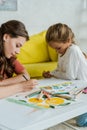 Focus of babysitter drawing near cute kid in living room Royalty Free Stock Photo