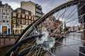 Selective focus on bicycle wheel with water drops with colorful buildings in the background blur in Amsterdam NETHERLANDS Royalty Free Stock Photo