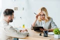 Focus of blonde recruiter in glasses looking at clipboard near bearded man