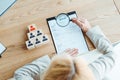 Focus of blonde recruiter holding magnifier near clipboard