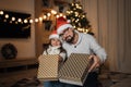 Focus on boxes with gifts, blured young happy father and little cute daughter in santa hats Royalty Free Stock Photo