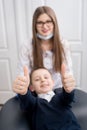 Focus of boy`s hands showing thumbs up gestures of good class. Doctor and child looks at camera Royalty Free Stock Photo