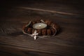 focus on a burning candle, around it a Buddhist wooden bracelet intertwined with a Christian cross