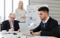 Focus on Business manager wearing eyeglass writing on paper and staff sitting typing and seeing on laptop near colour pens. Woman Royalty Free Stock Photo