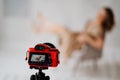 focus on camera. woman in a beige dress poses on a gray chair in a photo studio.