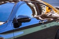 Car wing mirror with colorful reflection on surface of modern automobile black car