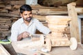 Focus on carpenter, young indian carpenter polising or shaping chariot by using carpentry tools at workplace - concept