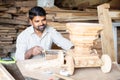 Focus on carpenter, young indian carpenter polising or shaping chariot by using carpentry tools at workplace - concept Royalty Free Stock Photo
