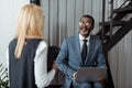 Focus of cheerful african american man in glasses looking at blonde woman while using laptop Royalty Free Stock Photo