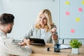 Focus of cheerful woman holding clipboard and gesturing near employee