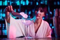 Focus on cocktail glass. Young girl, bartender working in bar, nightclub, making sweet and sour cocktail, putting ice