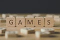 Focus of cubes with word games surrounded by blocks with letters on wooden surface isolated on black