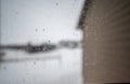 Focus on a dirty residential windo overlooking the side of a house and snow covered area