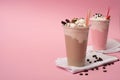 Focus of disposable cups of chocolate and strawberry milkshakes with coffee grains on napkins on pink background