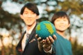 Focus Earth with blurred asian boy and businessman holding globe together. Gyre