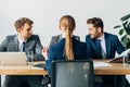 Focus of employee sitting at table near smiling recruiters in office