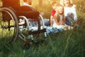 Focus on emply wheelchair on the foreground while happy family rest on the background