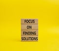 Focus on finding solutions symbol. Concept words Focus on finding solutions on wooden blocks. Beautiful yellow background. Royalty Free Stock Photo