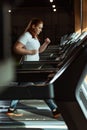 Focus of focused overweight girl running on treadmill in gym