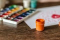 Gouache, watercolor paints and a white sheet with a pattern on a wooden table. Royalty Free Stock Photo