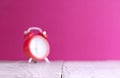 Focus on front with blurred clock on light wooden table with colorful background. Time for wake up Royalty Free Stock Photo