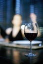 Focus on a glass of red wine with a woman in the background Royalty Free Stock Photo