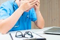 Focus on the glasses, tired Doctor sits at a table