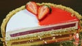 Focus in at half of round cheesecake with red jelly interlayer and colorful icing