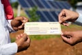 focus on hand, close up shot of farmer receiving check from banker in front of solar panel - concept of financial Royalty Free Stock Photo