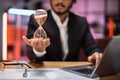 Focus on hand of smiling confident businessman holding hourglass Royalty Free Stock Photo