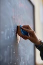 Focus on hand of young student or teacher wiping blackboard with wet sponge