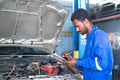 focus on hands Car mechanic noting repair parts during open car hood engine repair at garage - concept of customer Royalty Free Stock Photo