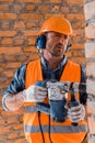 Focus of handsome and bearded constructor holding hammer drill near brick wall Royalty Free Stock Photo