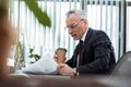 Focus of handsome businessman reading newspaper while holding disposable cup Royalty Free Stock Photo