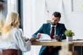 Focus of handsome recruiter looking at blonde employee